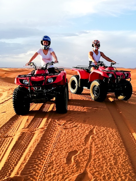 People riding quad bikes on sand dunes in Agafay Desert, Marrakech.