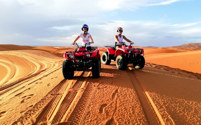 People riding quad bikes on sand dunes in Agafay Desert, Marrakech.