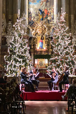 String quartet performing at St. Peter's Church, Vienna, with Christmas trees and festive decor.