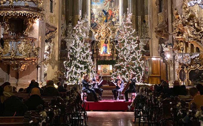String quartet performing at St. Peter's Church, Vienna, with Christmas trees and festive decor.