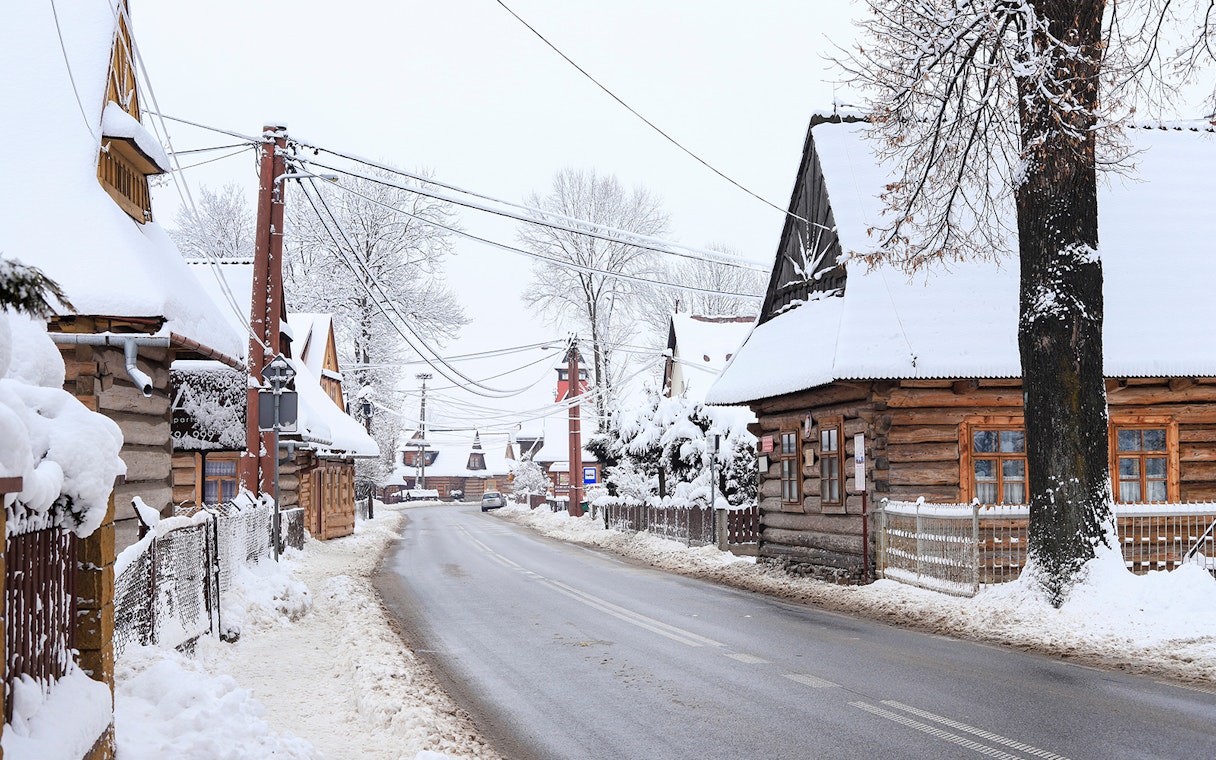 Snow-covered wooden houses in a village near Zakopane, Poland, during a winter tour from Krakow.
