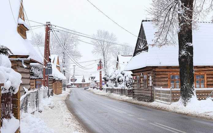 Snow-covered wooden houses in a village near Zakopane, Poland, during a winter tour from Krakow.