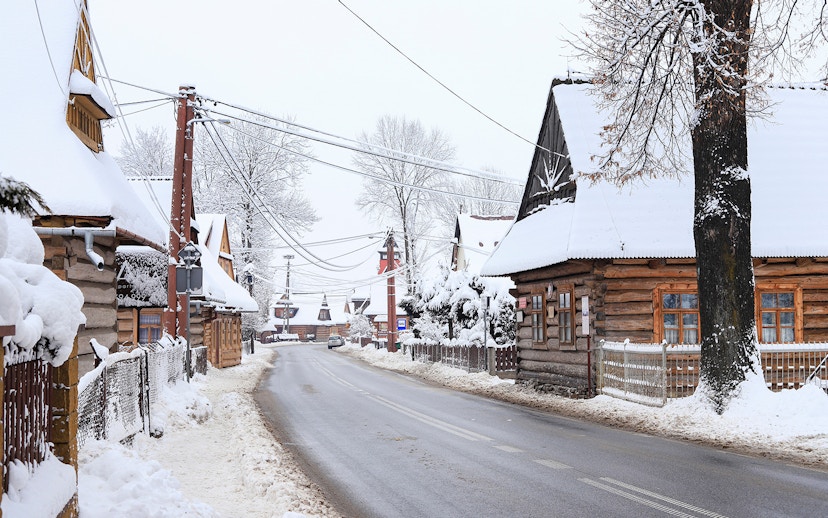 Snow-covered wooden houses in a village near Zakopane, Poland, during a winter tour from Krakow.