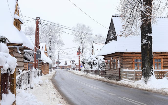 Snow-covered wooden houses in a village near Zakopane, Poland, during a winter tour from Krakow.