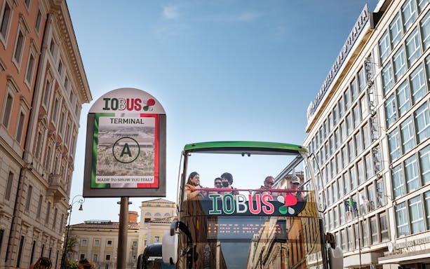 People enjoying Rome Hop-On Hop-Off bus tour near city buildings.