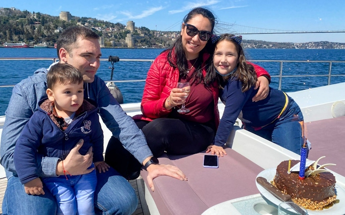 Family enjoying Istanbul Bosphorus cruise with Rumeli Fortress in the background.