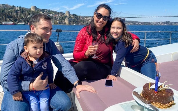 Family enjoying Istanbul Bosphorus cruise with Rumeli Fortress in the background.