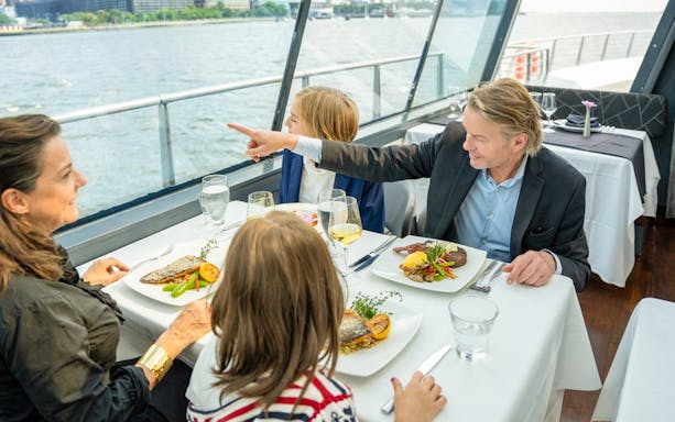 Family dining on a cruise ship with a view of the water.