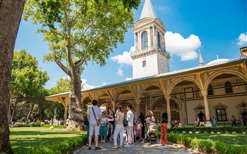 Tour group exploring Topkapi Palace courtyard in Istanbul.