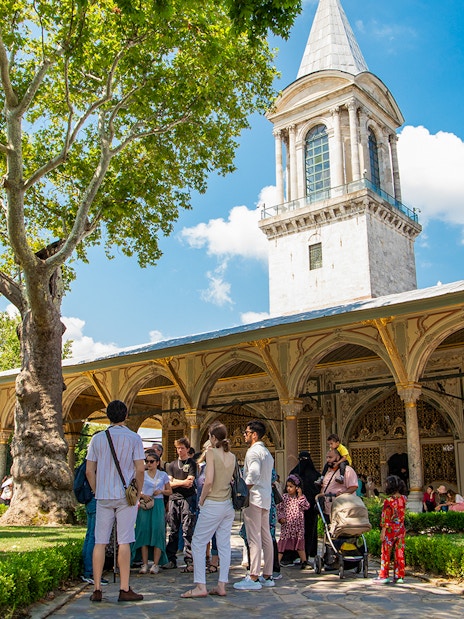 Tour group exploring Topkapi Palace courtyard in Istanbul.