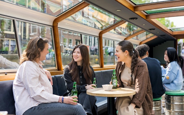 People enjoying drinks on a Heineken cruise in Amsterdam canal boat.
