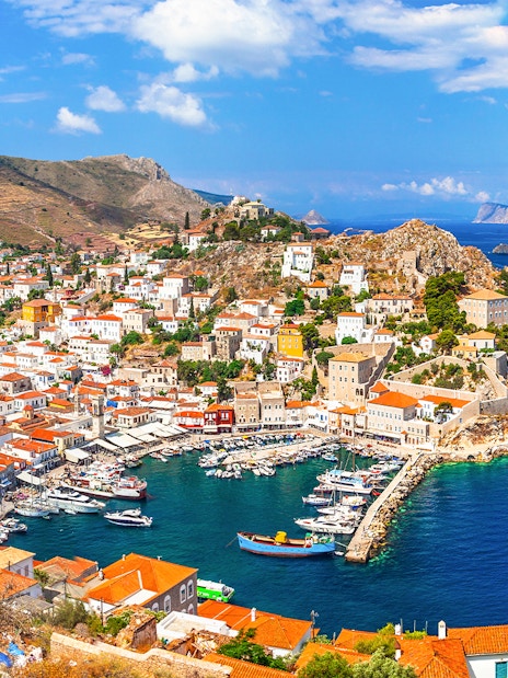 Aerial view of Hydra Island's harbor with boats and hillside houses, Greece.