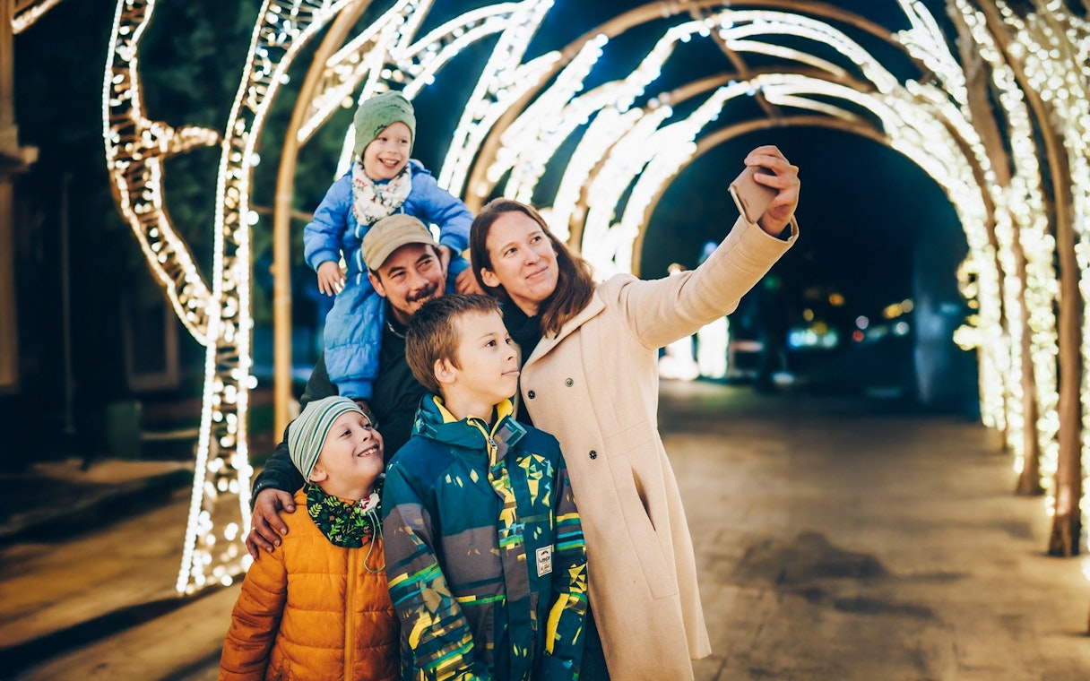Family taking a selfie under illuminated arches at Lumina Park, Budapest.