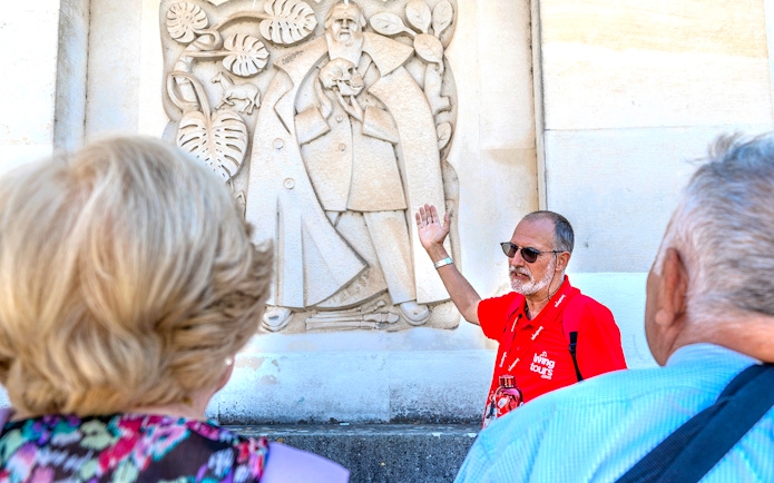 Tour guide explaining a stone relief in Coimbra during Fátima & Coimbra full-day tour from Porto.