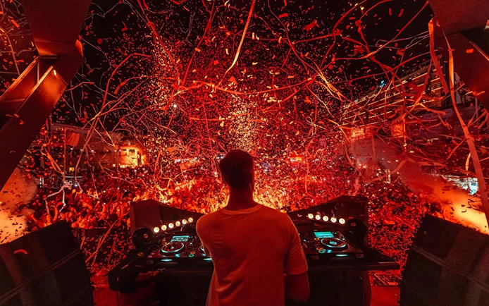 DJ performing at Ushuaïa Ibiza with vibrant confetti and crowd.