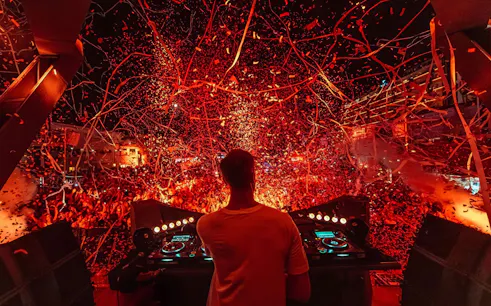 DJ performing at Ushuaïa Ibiza with vibrant confetti and crowd.