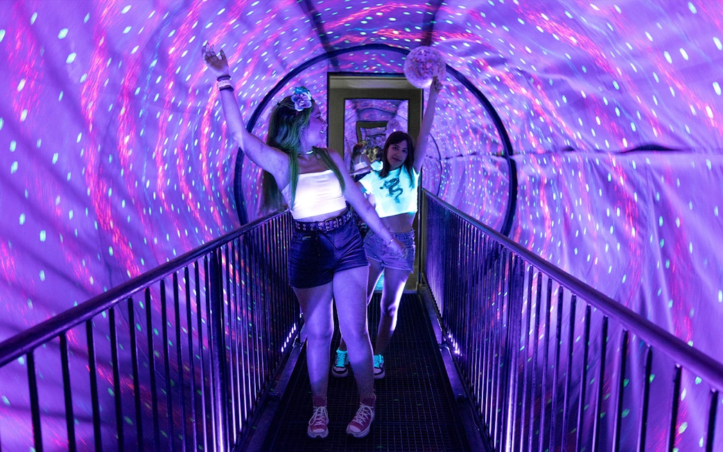 Visitors walking through a colorful tunnel at the Museum of Illusions in Madrid.