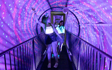 Visitors walking through a colorful tunnel at the Museum of Illusions in Madrid.