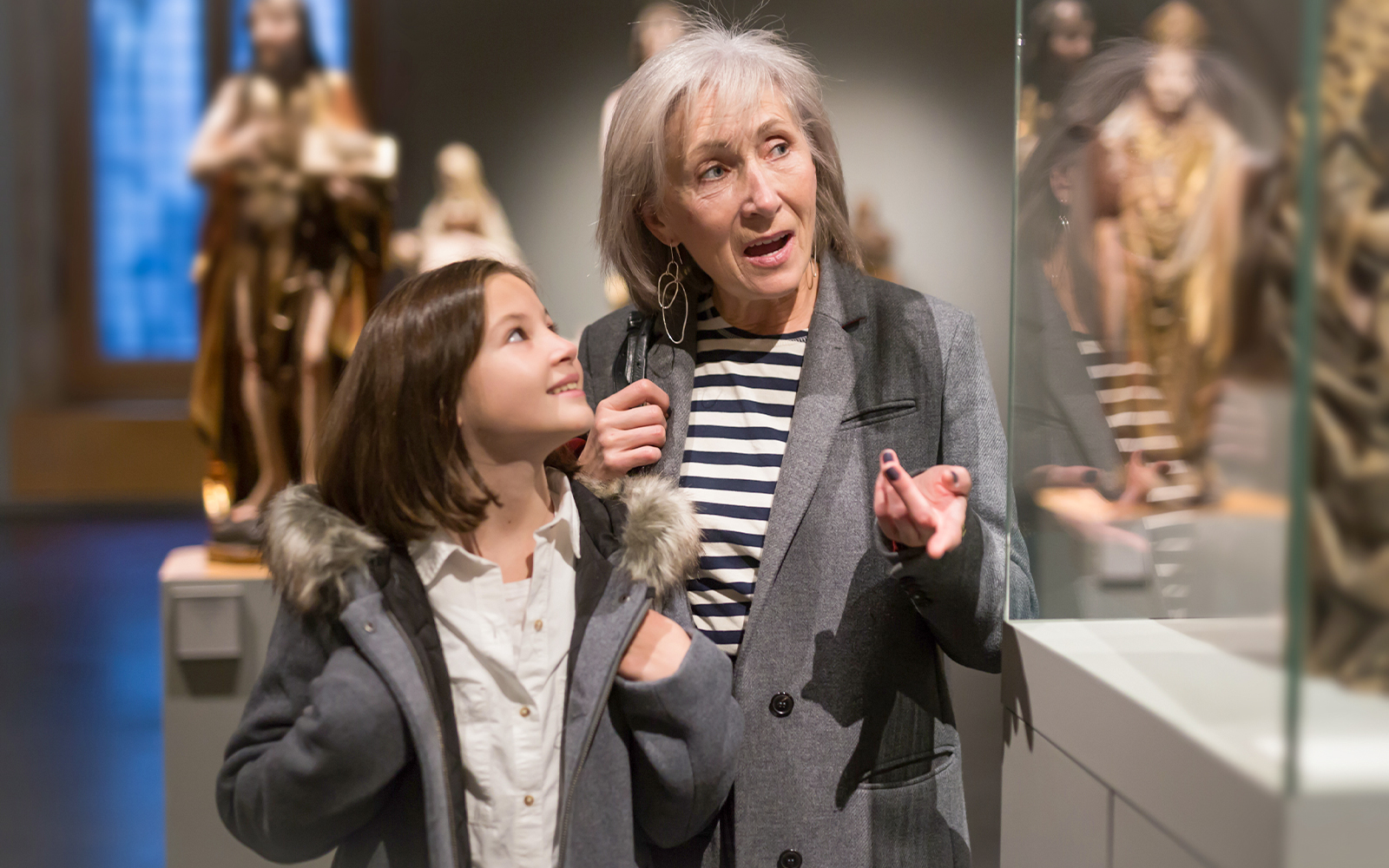 Girl and grandmother exploring ancient sculptures at a museum.