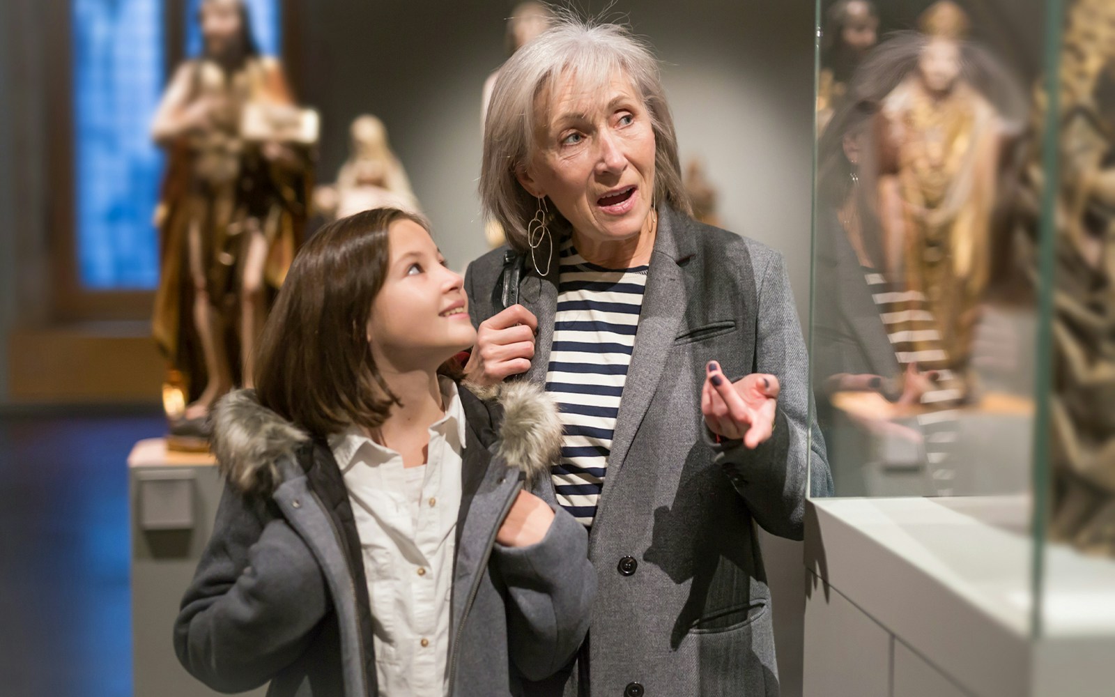 Girl and grandmother exploring ancient sculptures in a museum exhibit.