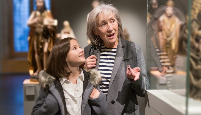 Girl and grandmother exploring ancient sculptures at a museum.