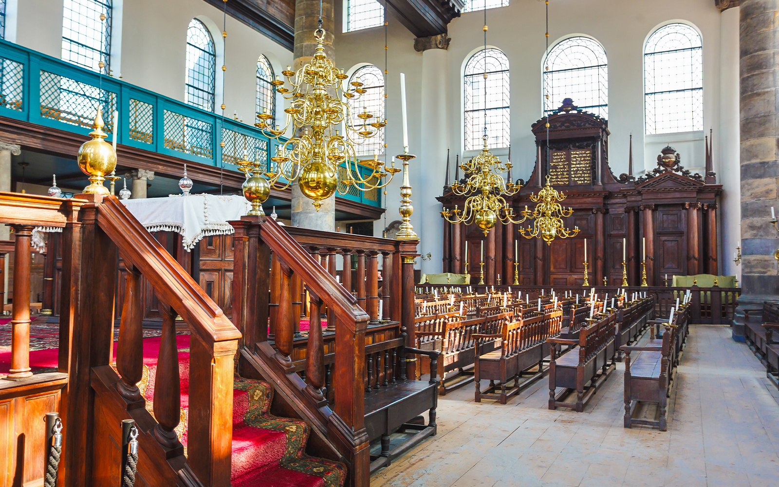Interior of historic synagogue with wooden pews and chandeliers, part of Anne Frank walking tour.