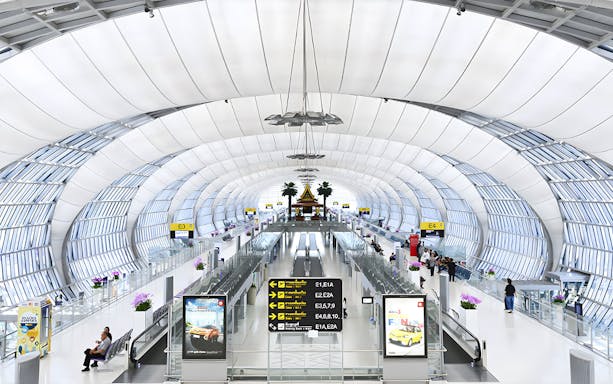 Suvarnabhumi Airport terminal interior with travelers and signage for VIP Fast-Track Service.