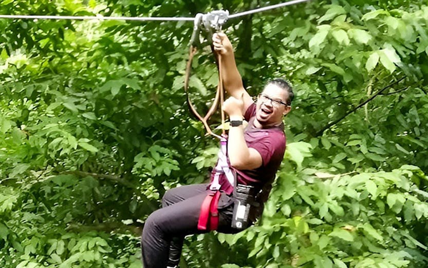 Person ziplining through lush forest at SKYTREX Adventure Langkawi.
