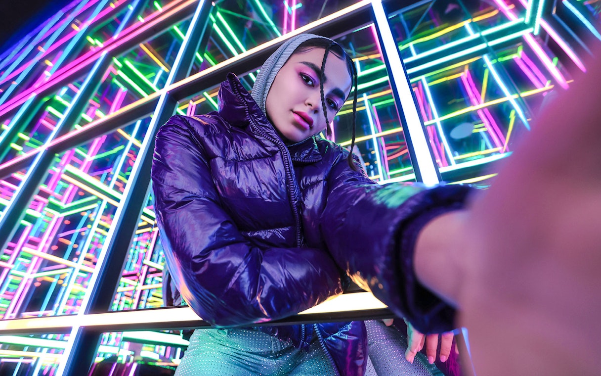 Person posing in front of vibrant neon lights at House of Hype.