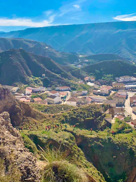 Hikers exploring trails in Geopark Granada with mountainous landscape and village below.