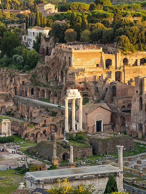 Tourists exploring Palatine Hill with Roman Forum ruins in Rome, Italy.