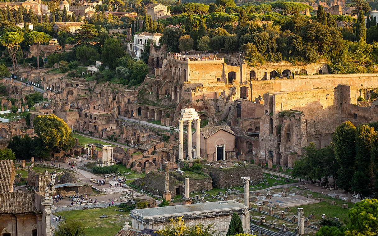 Tourists exploring Palatine Hill with Roman Forum ruins in Rome, Italy.
