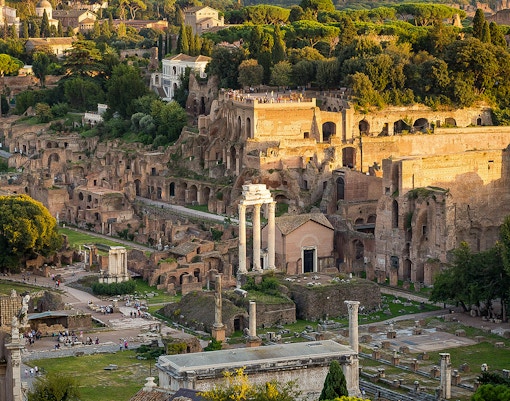 Tourists exploring Palatine Hill with Roman Forum ruins in Rome, Italy.