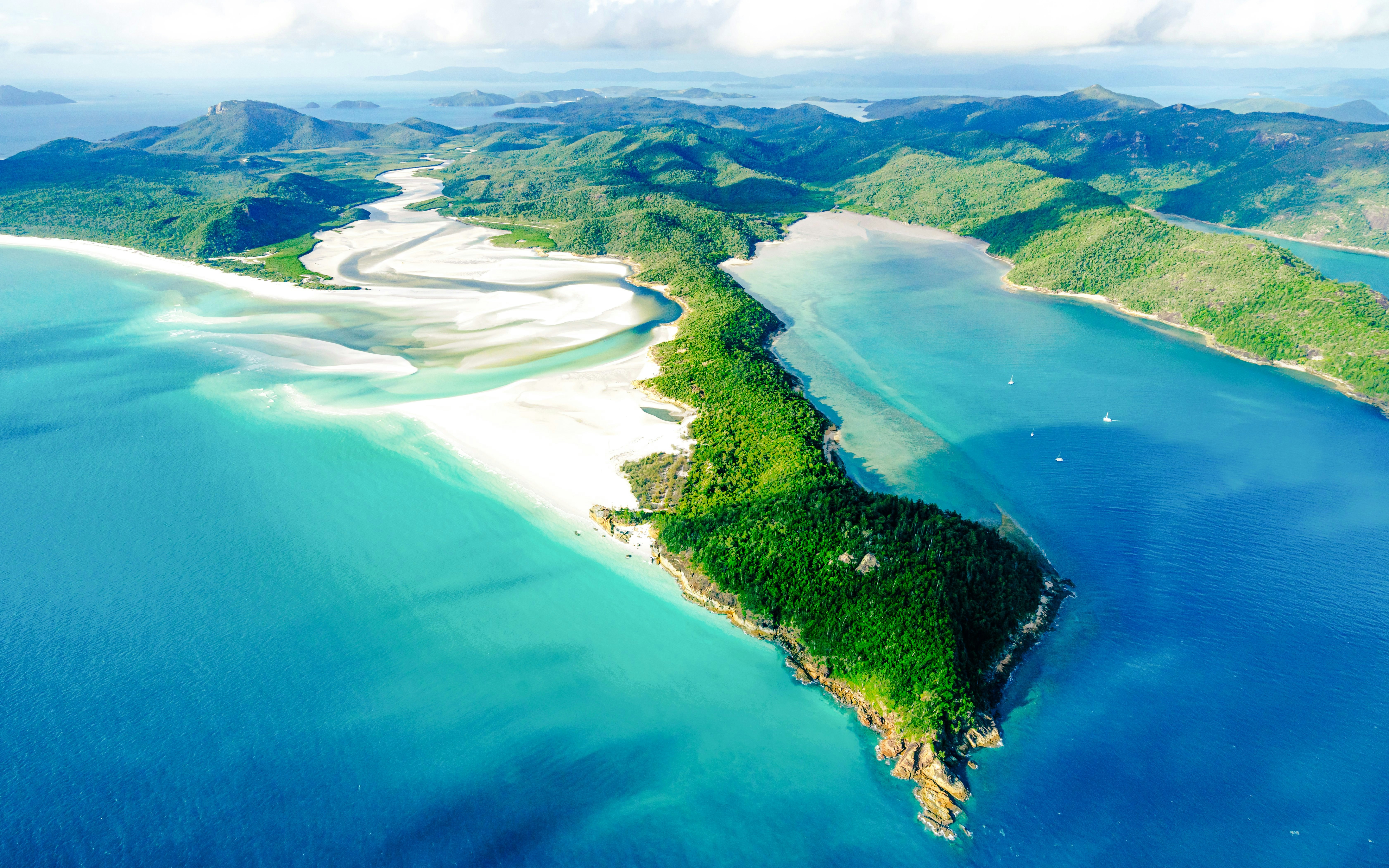 Aerial view of Hill Inlet and Whitehaven Beach, Whitsunday Islands, with turquoise waters and lush greenery.