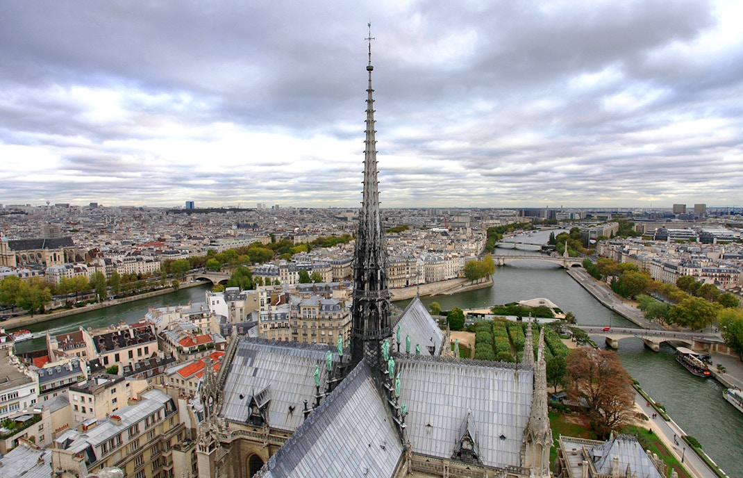 Notre Dame Cathedral spire in Paris, France, viewed from below against a clear sky.