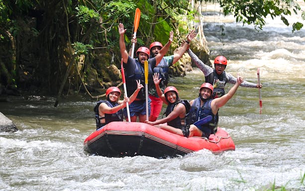 Group rafting on Ayung River, Bali, with paddles raised in excitement.