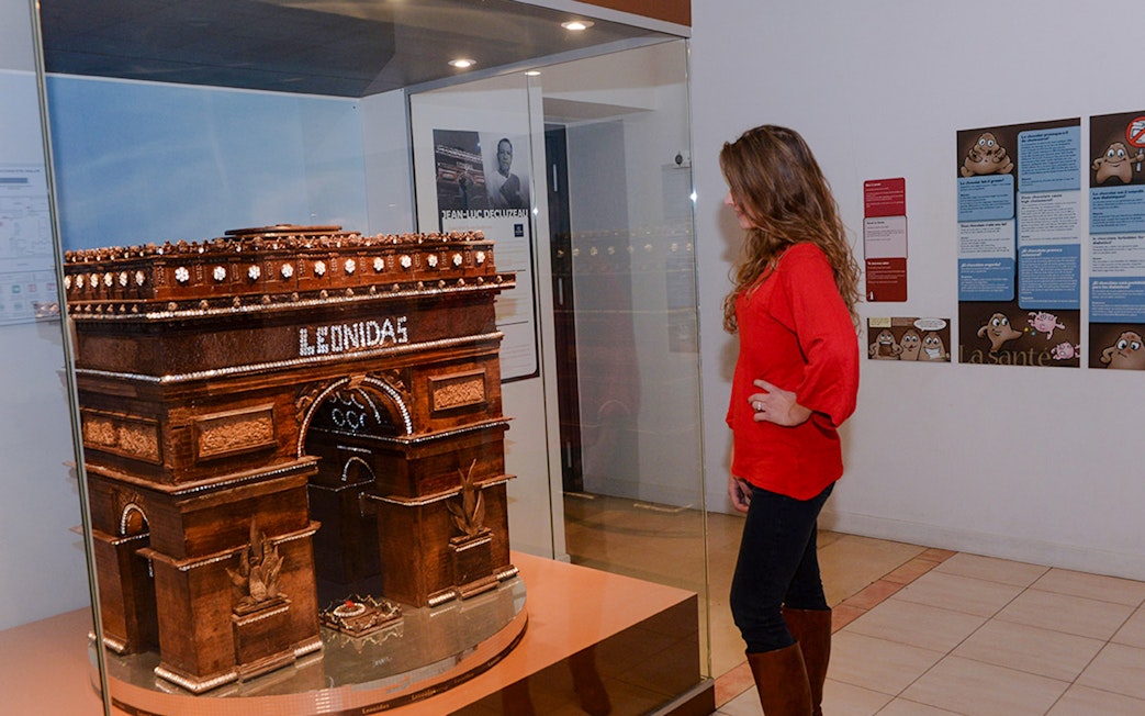 Woman observing chocolate Arc de Triomphe at Choco-Story Paris museum.