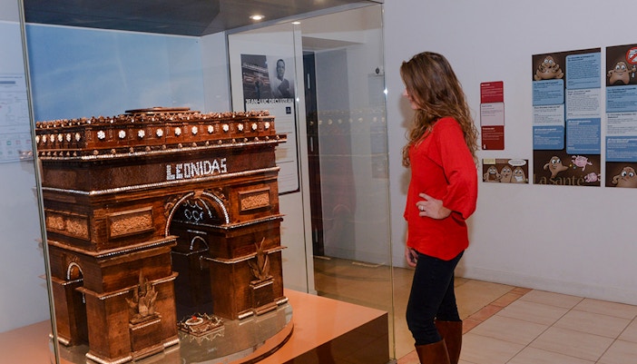 Woman observing chocolate Arc de Triomphe at Choco-Story Paris museum.