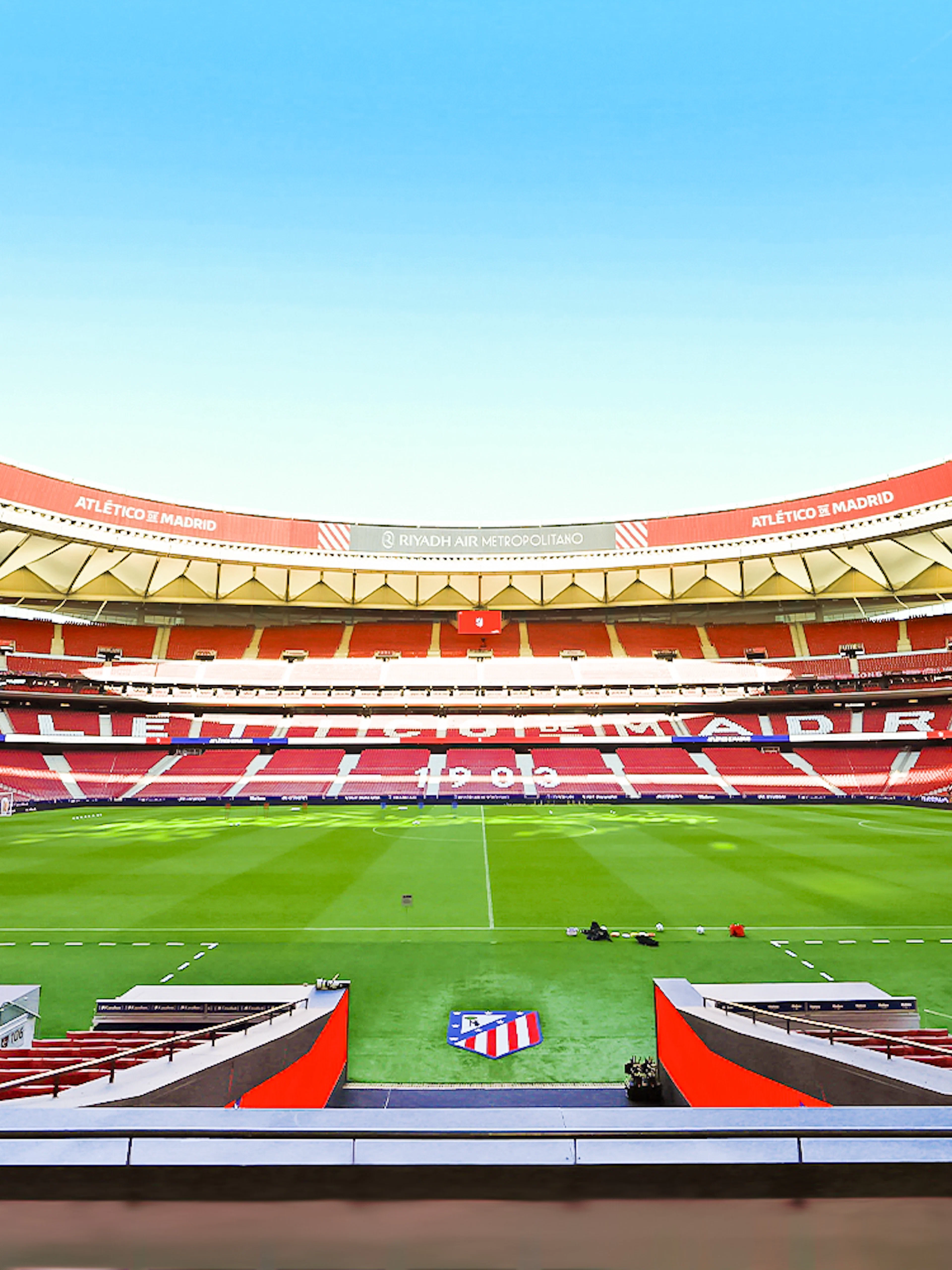 Atlético de Madrid stadium interior with empty seats and green field.