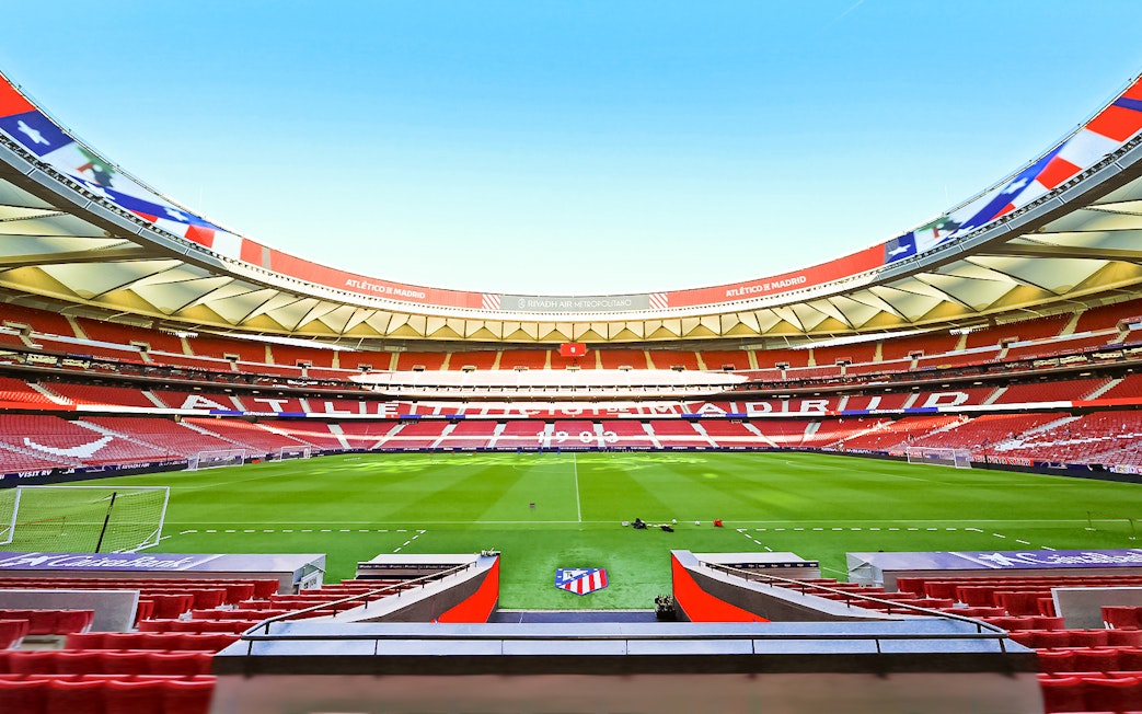 Atlético de Madrid stadium interior with empty seats and green field.