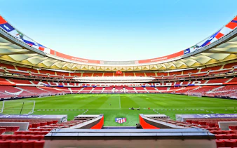 Atlético de Madrid stadium interior with empty seats and green field.