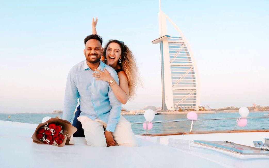Couple on a private yacht near Burj Al Arab, Dubai with a bouquet of roses.