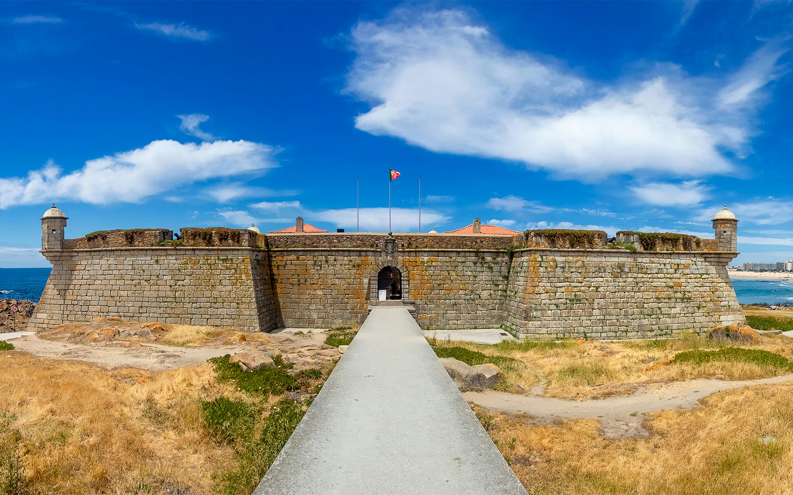 Hop-on hop-off bus near Porto's Fort of São Francisco with tourists exploring the historic site.