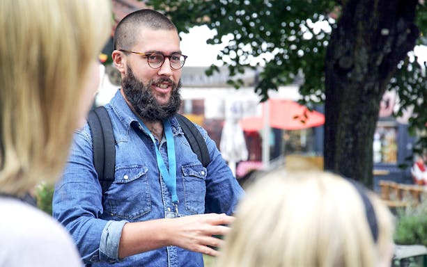 Guide explaining local history to tourists outdoors.
