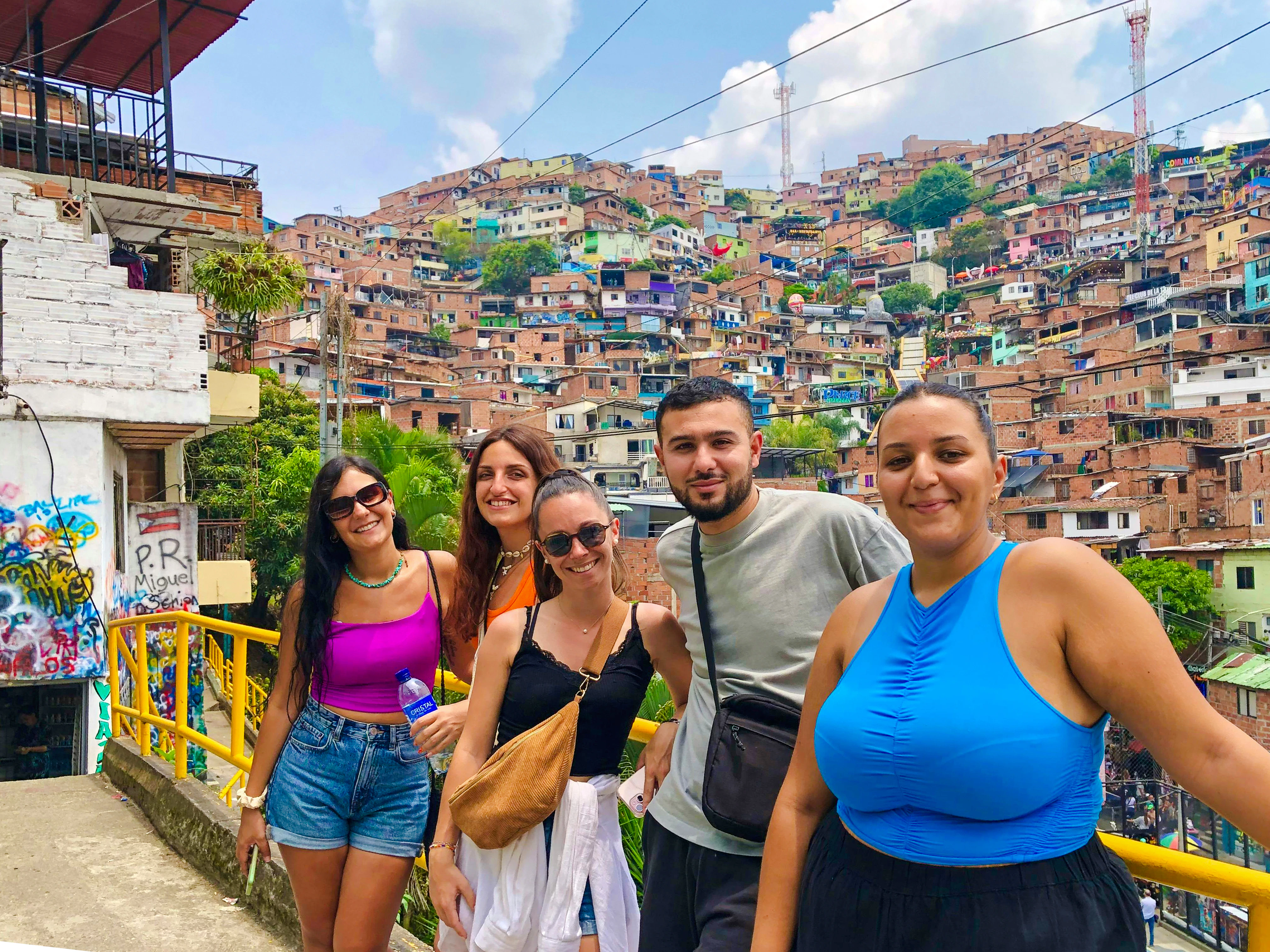Guests exploring Medellin Comuna with colorful hillside houses in the background.