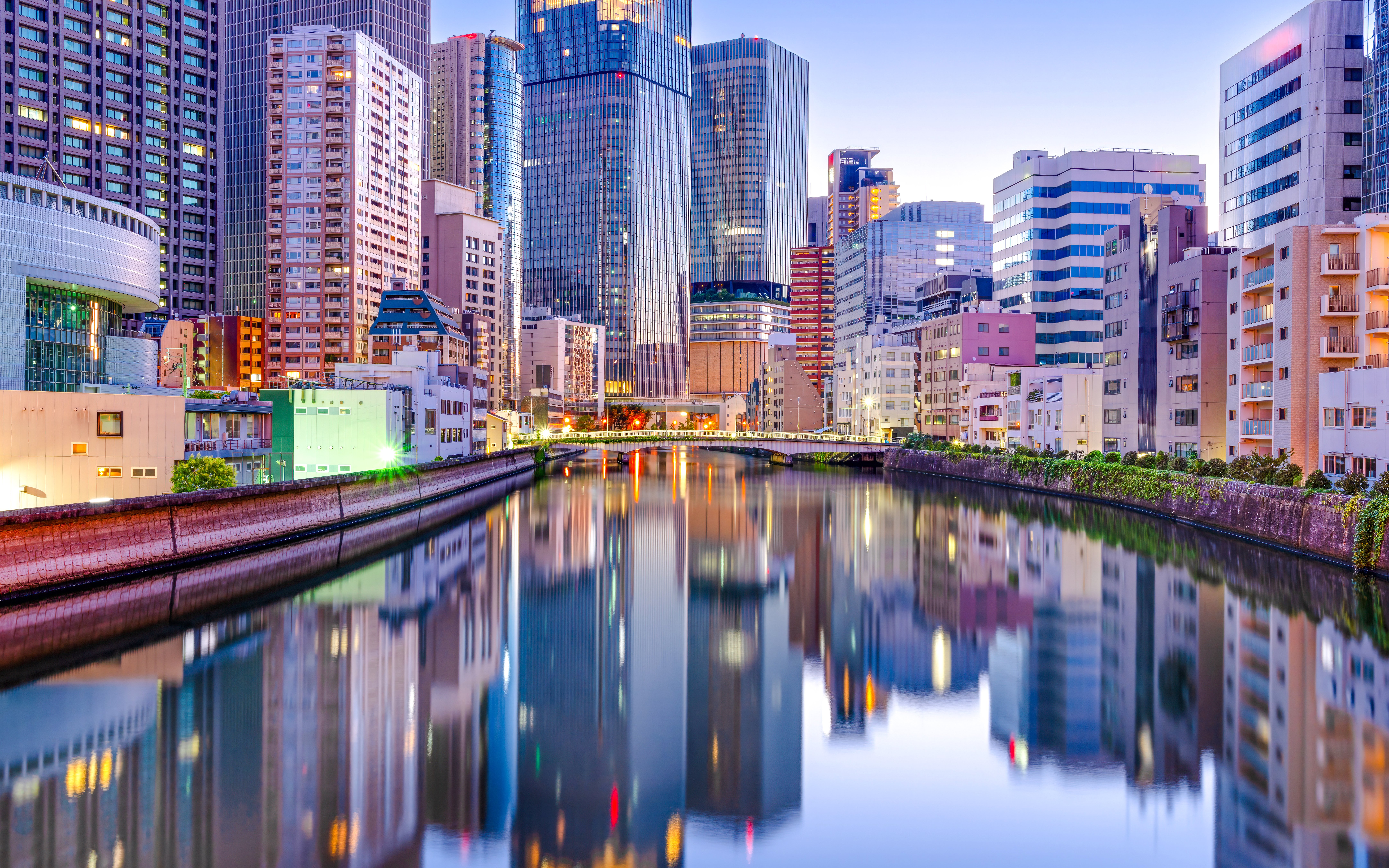 Tenmabashi Riverside skyline with modern buildings reflecting in the water at dusk.