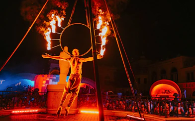Fire performer at Sparty bath party in Budapest with colorful lights and crowd.