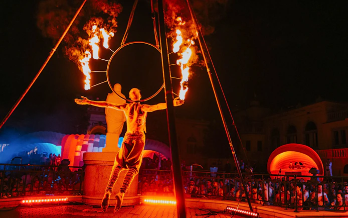 Fire performer at Sparty bath party in Budapest with colorful lights and crowd.
