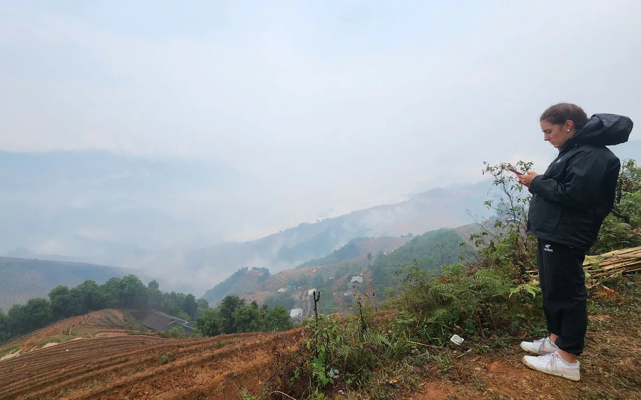 Person overlooking terraced rice fields and misty hills in Mu Cang Chai, Vietnam.