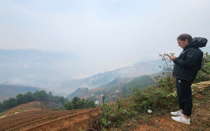 Person overlooking terraced rice fields and misty hills in Mu Cang Chai, Vietnam.